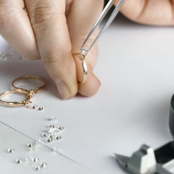 A person is working on a ring with a pair of pliers.