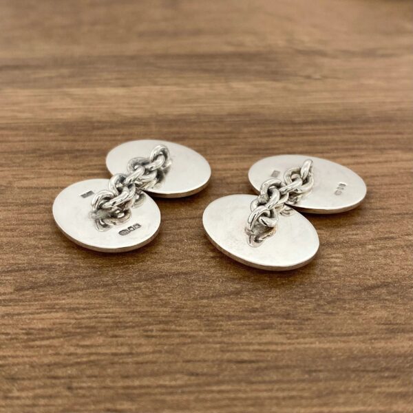 Pair of silver cufflinks with chain connection.