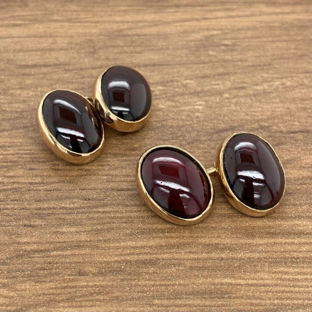 A pair of gold cufflinks with red and black stones.