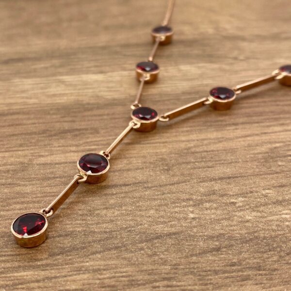 Gold necklace with red gemstone accents.