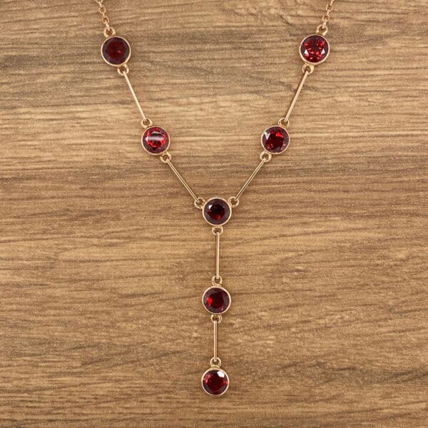 Gold necklace with red gemstone accents.
