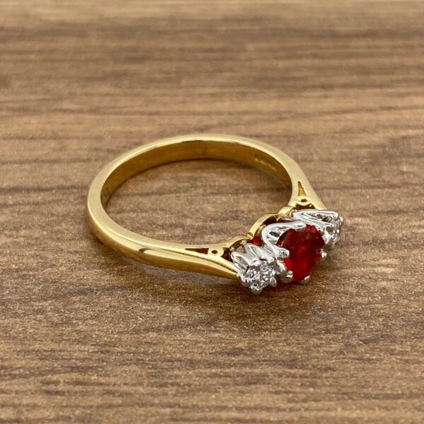 Gold ring with red gemstone and diamonds.