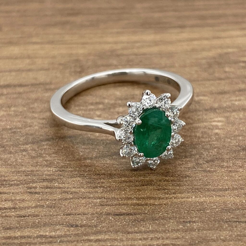 Emerald and diamond ring on wood background.