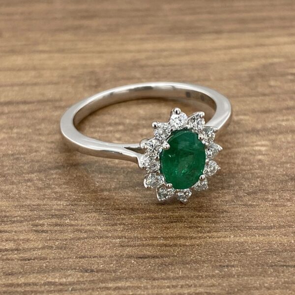Emerald and diamond ring on wood background.