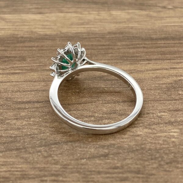 Emerald and diamond ring on wood background.