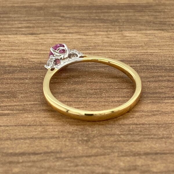 Gold ring with pink gemstone and diamonds.