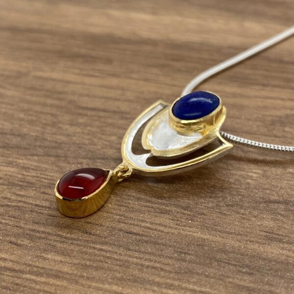 Silver and gold pendant with blue and red stones.