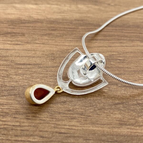 Back of silver necklace with red gem.