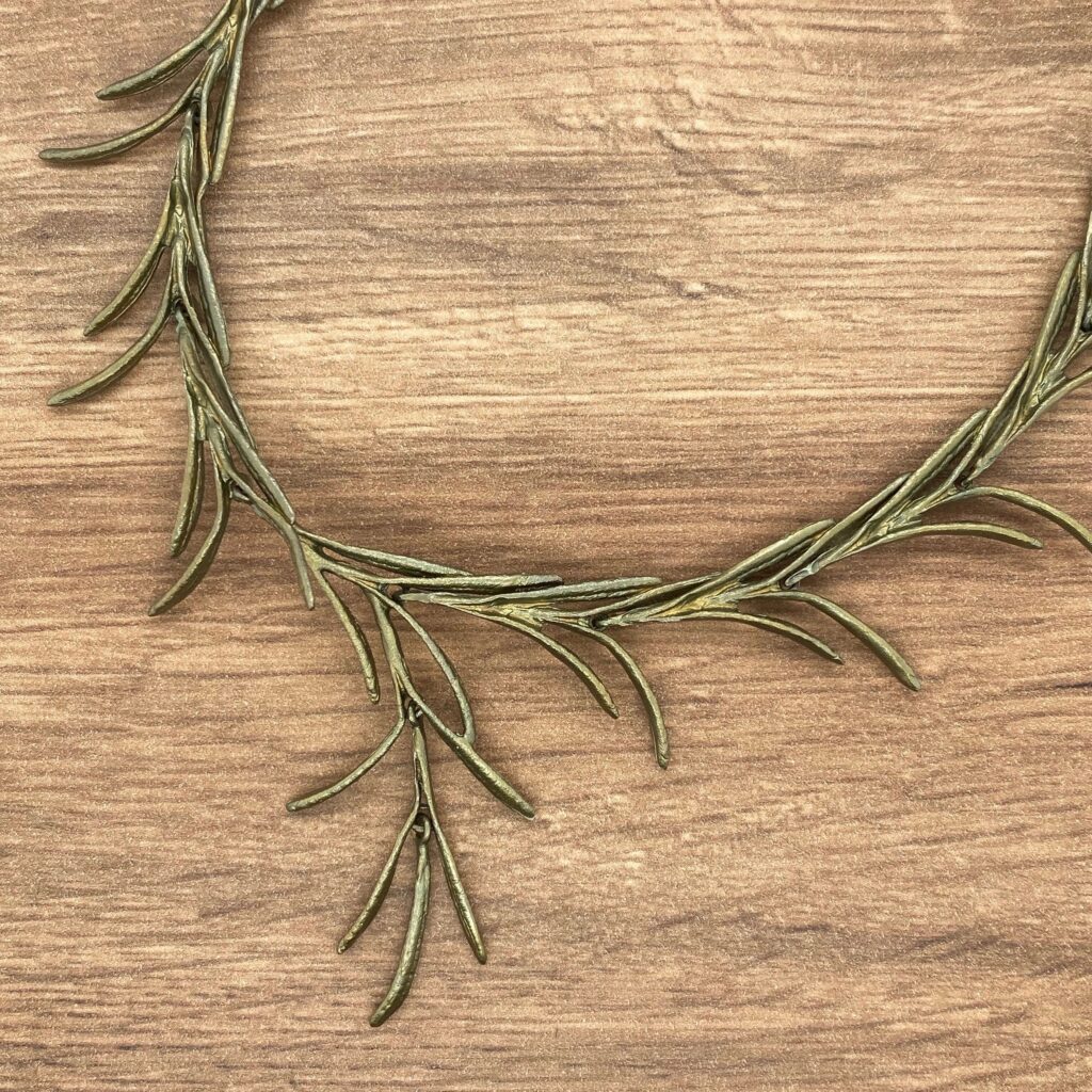 Gold rosemary branch necklace on wood.