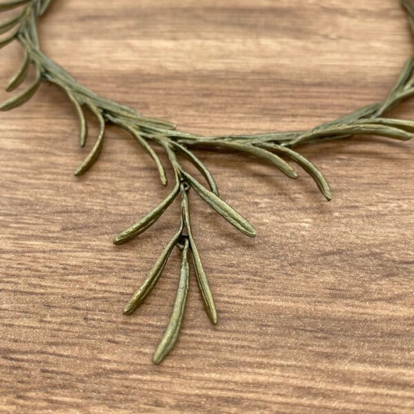 Gold twig necklace on a wooden surface.