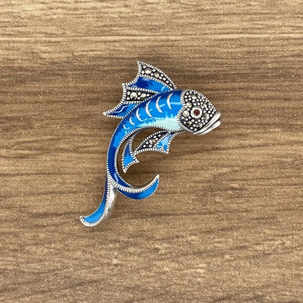An Aquamarine & Diamond Large Oval Cluster Earrings brooch on a wooden table.