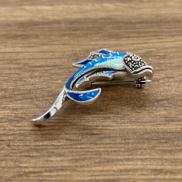 An Aquamarine & Diamond Large Oval Cluster Earrings brooch on a wooden table.