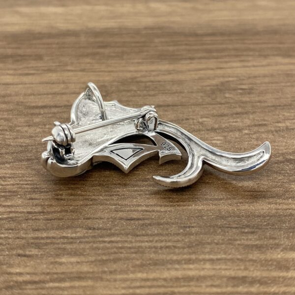 An Aquamarine & Diamond Large Oval Cluster Earrings brooch on a wooden table.
