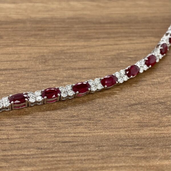 A ruby and diamond necklace on a wooden table.