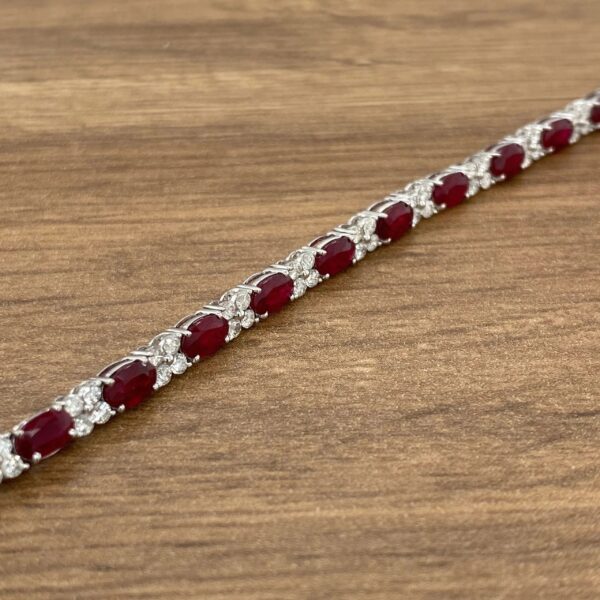 A ruby and diamond necklace on a wooden table.