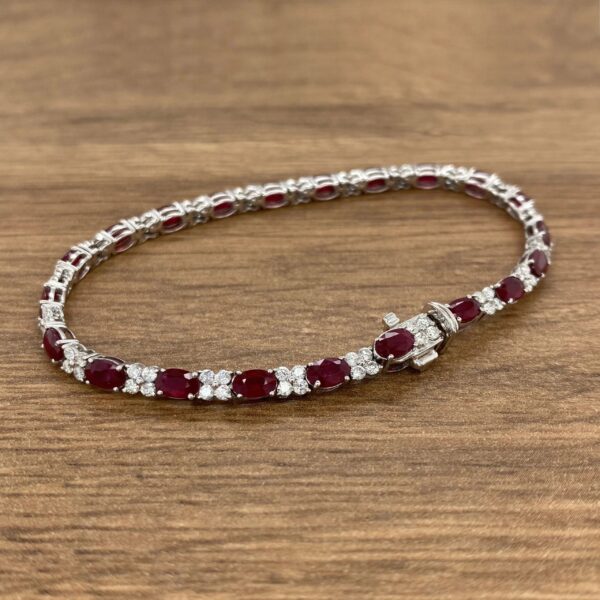 A ruby and diamond necklace on a wooden table.