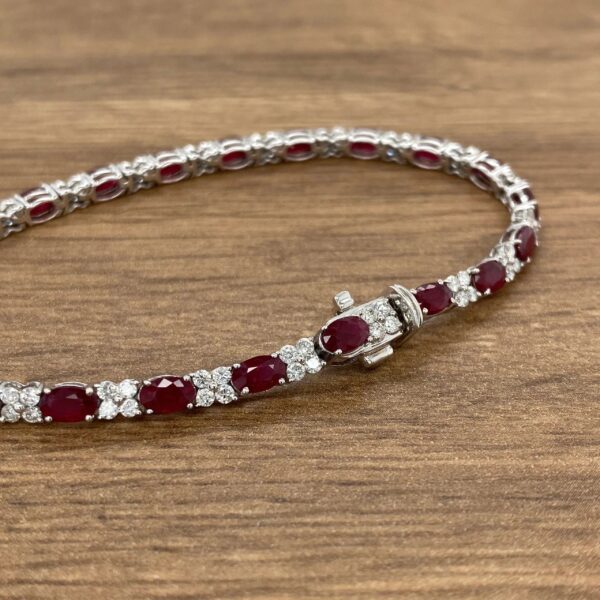 A ruby and diamond necklace on a wooden table.