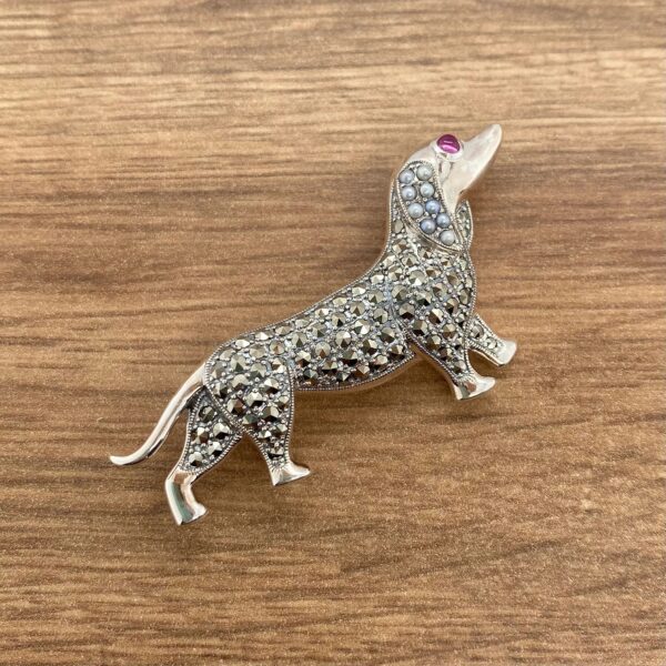 Silver dachshund brooch with red eyes.