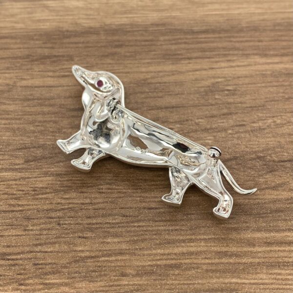 Silver dachshund brooch with ruby eye.