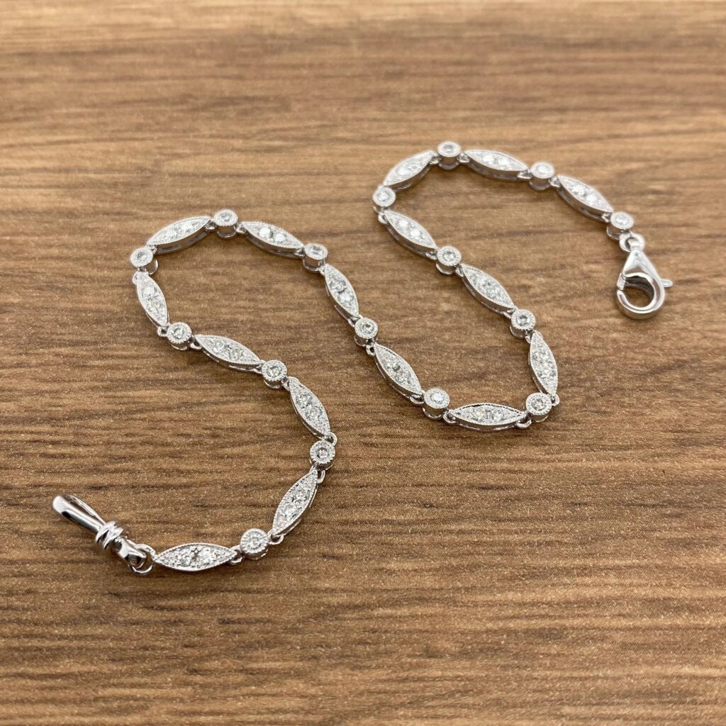 A silver bracelet with diamonds on it with a wooden background.