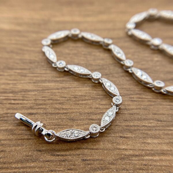 A silver bracelet with diamonds on it with a wooden background.