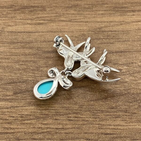 Silver swallow brooch with turquoise stone.