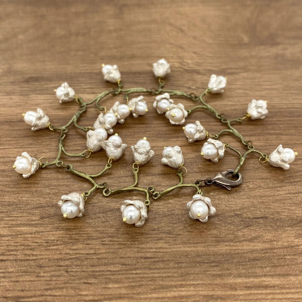 A bracelet with white pearls on a wooden table.