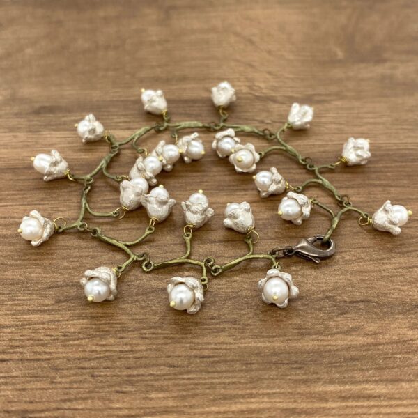 A bracelet with white pearls on a wooden table.