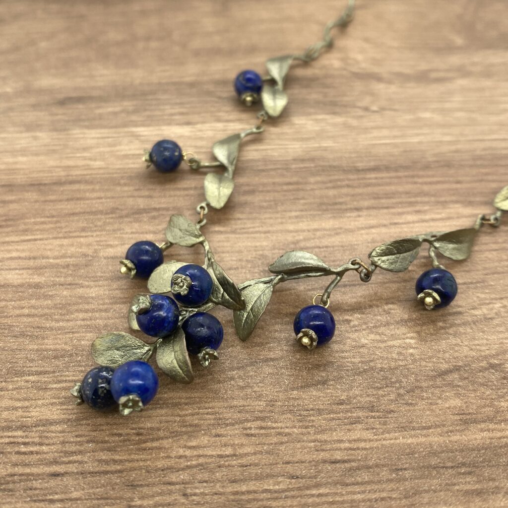 Silver necklace with blue gemstone berries.