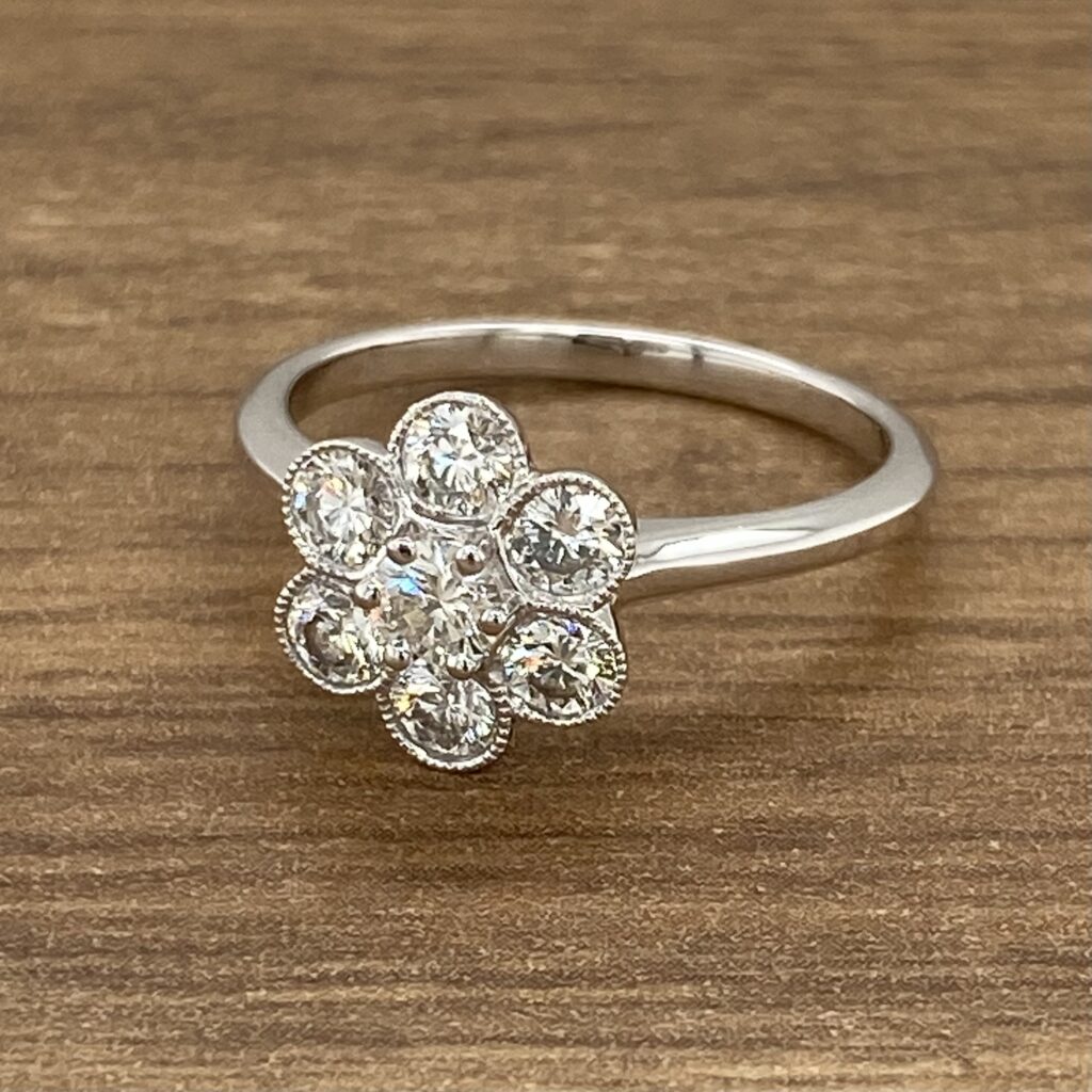Diamond flower ring on wooden surface.