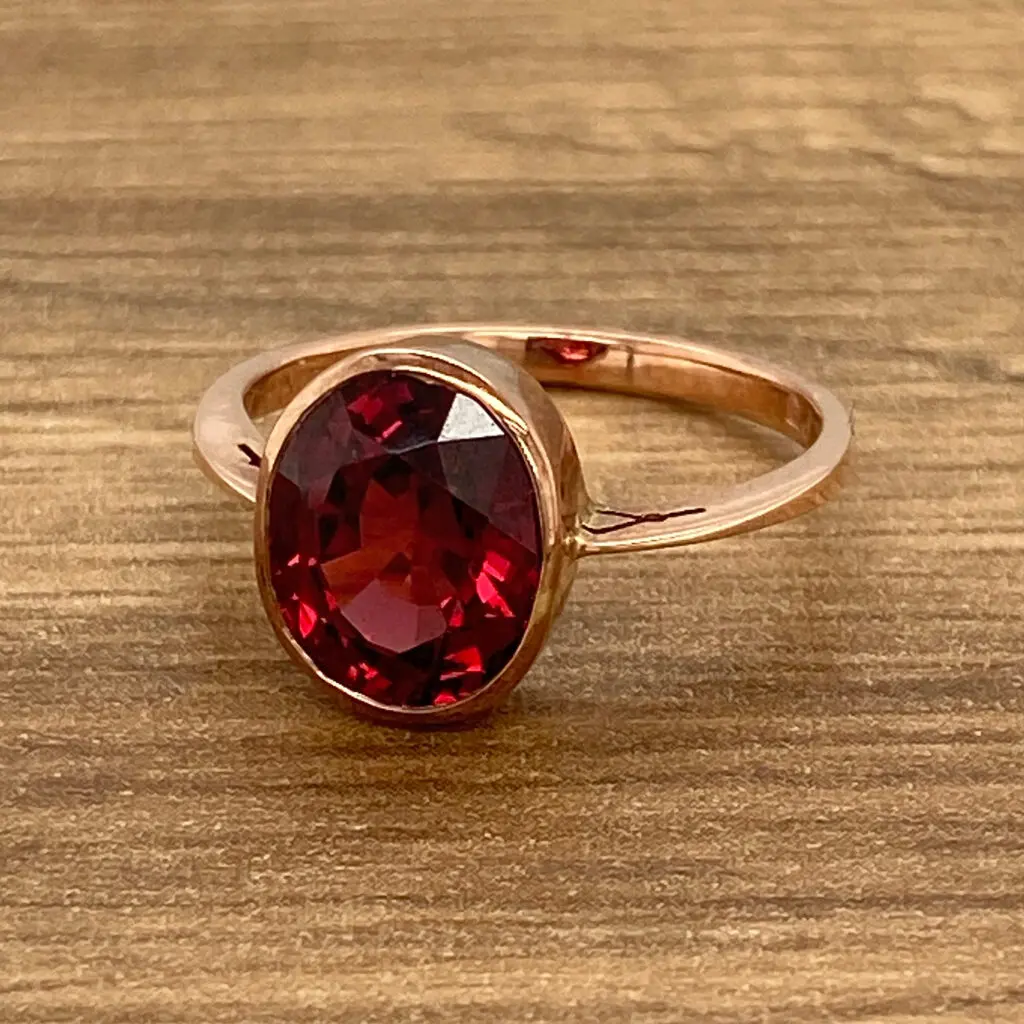Rose gold ring with red gemstone.