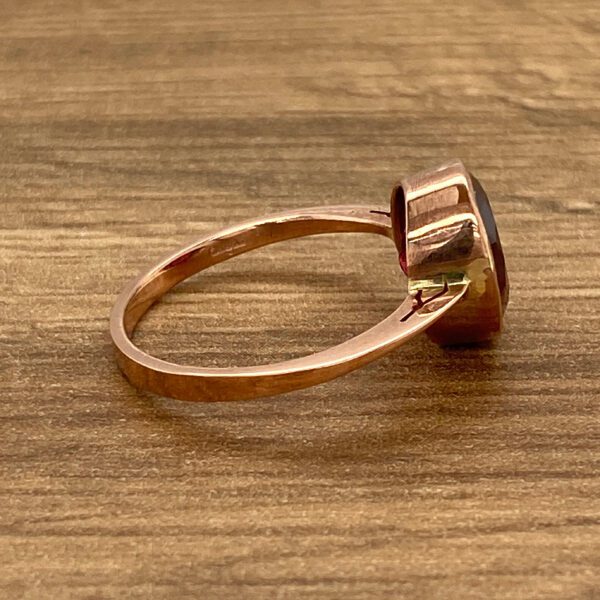 Rose gold ring with red gemstone.