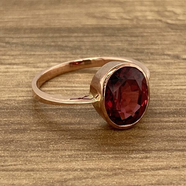 Rose gold ring with red gemstone.