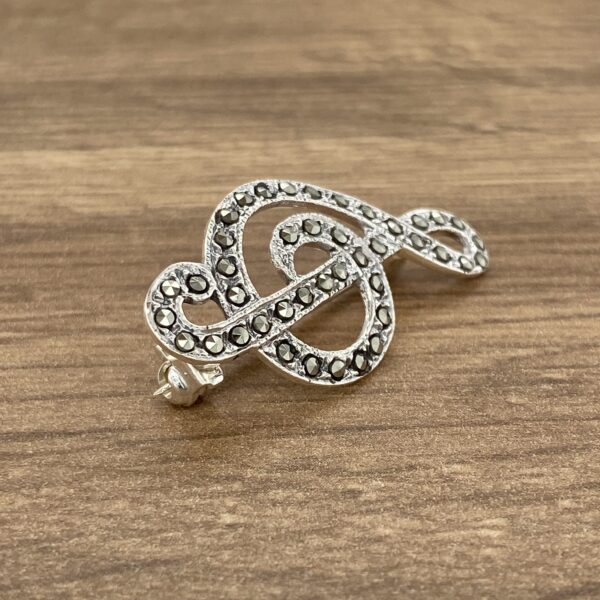 A silver musical note brooch with black diamonds.