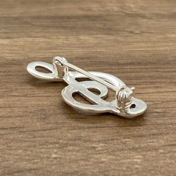 A silver musical note brooch with black diamonds.