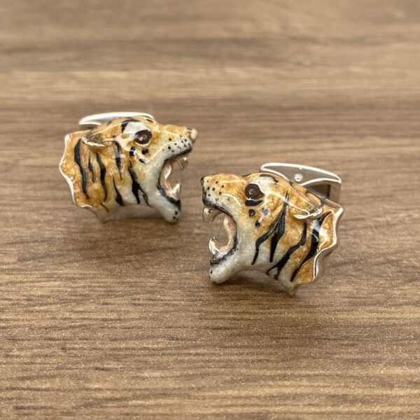 Two silver tiger head cufflinks.