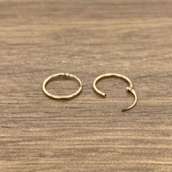 Two gold hoop earrings on wood.