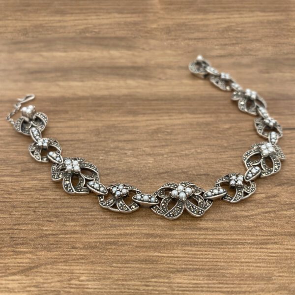 Silver and pearl floral bracelet on wood.