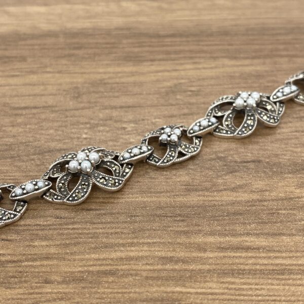 Silver and pearl floral bracelet on wood.
