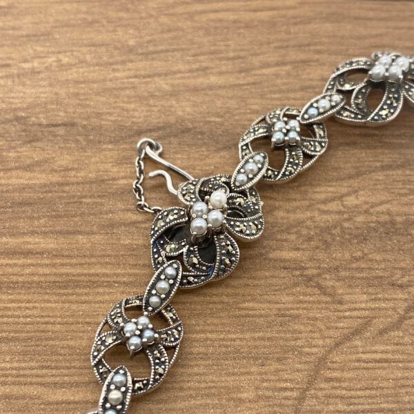 Silver bracelet with floral and pearl design.