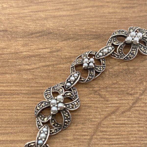 Silver and pearl floral bracelet on wood.