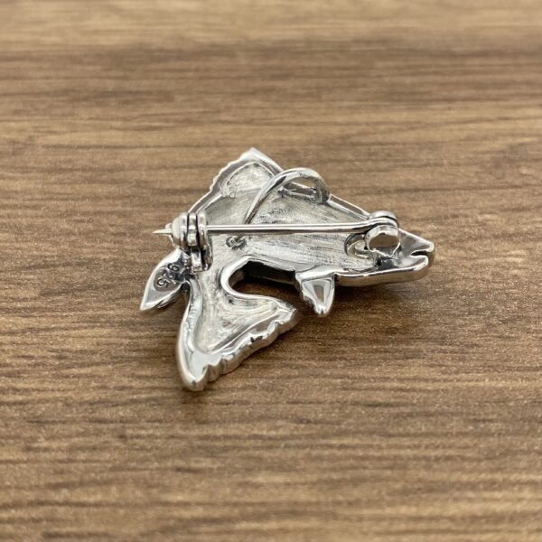 A colorful fish brooch on a wooden table.
