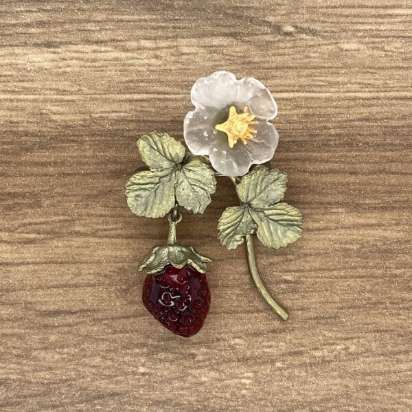 A glass strawberry and flower brooch.
