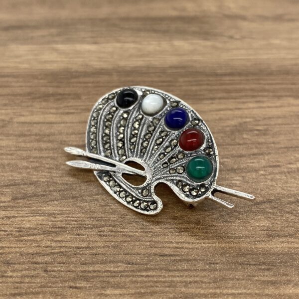 Silver palette brooch with colorful stones.