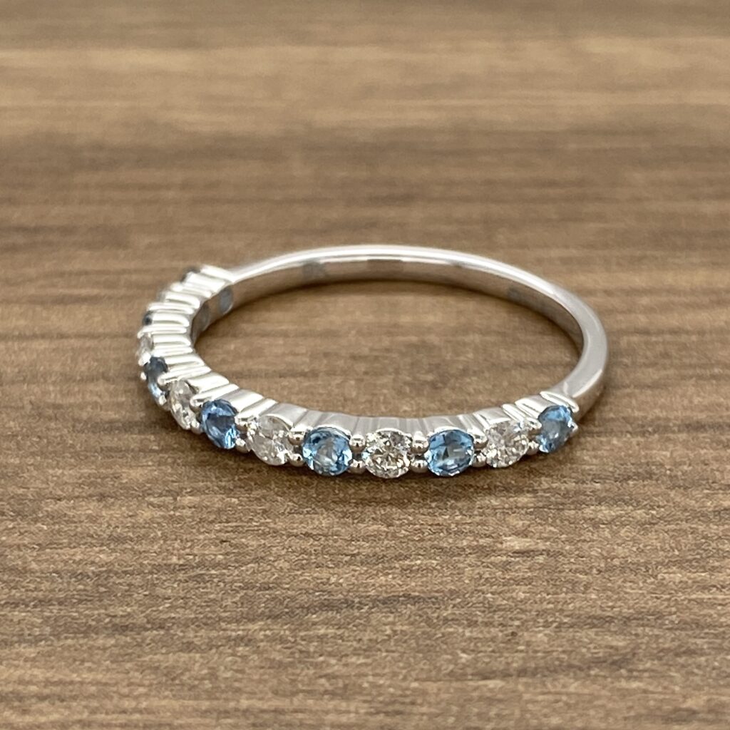 A blue topaz and diamond ring on a wooden table.