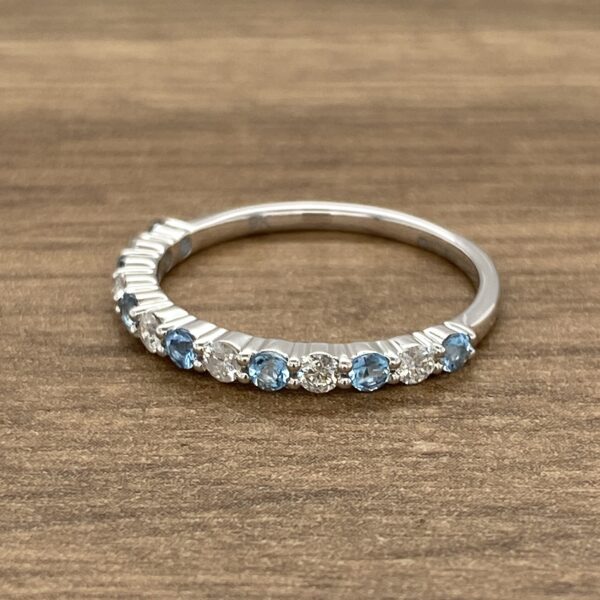 A blue topaz and diamond ring on a wooden table.