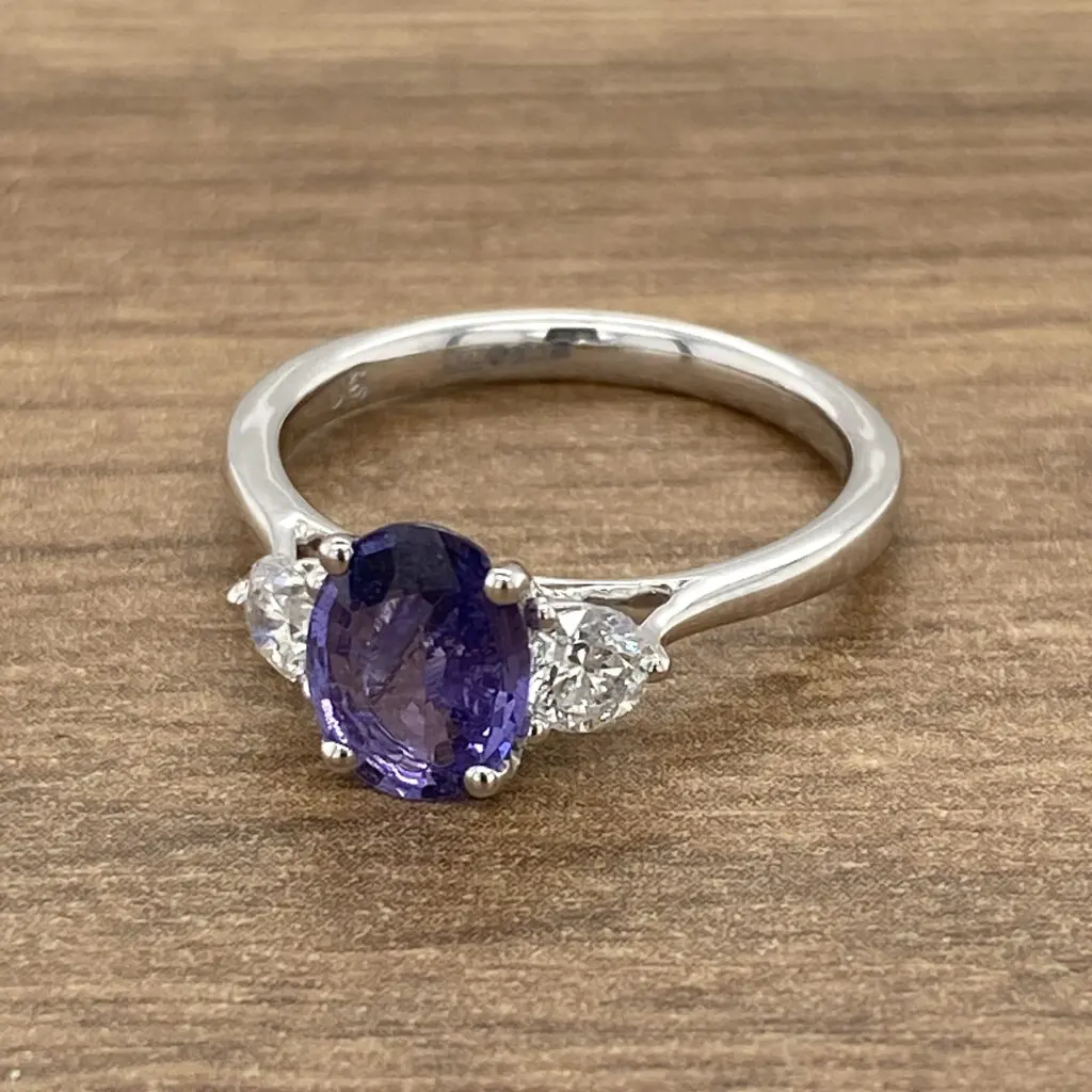 A tanzanite and diamond ring on a wooden table.