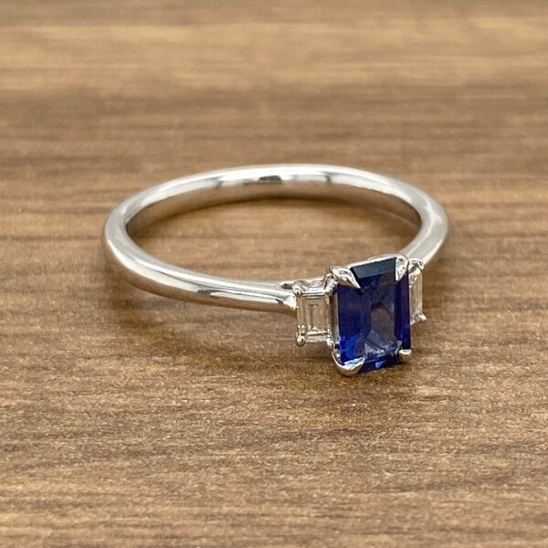Blue sapphire and diamond ring on wood.
