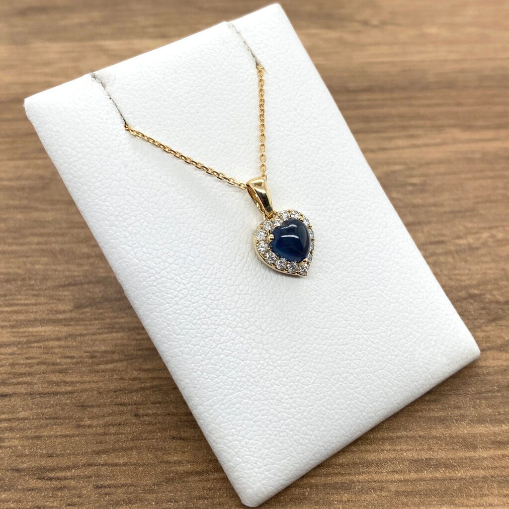 Gold heart necklace with blue gemstone.
