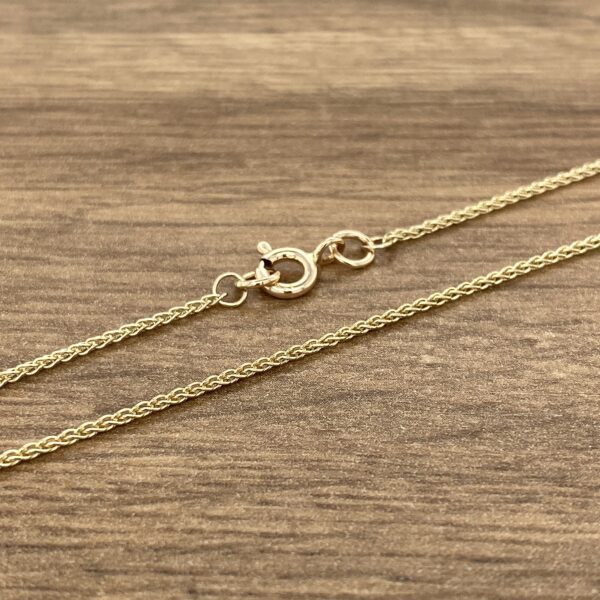 A gold chain on a wood surface.